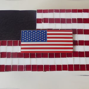 May include: A red, white, and blue American flag mosaic with a black background. The flag is made of small square tiles.