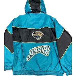 May include: A teal and black hooded jacket featuring the Jacksonville Jaguars logo and text on the back. The design includes a large embroidered jaguar head emblem above the team name in white, teal, and gold lettering with black outlines.