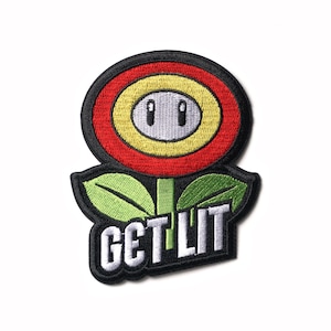 Op de afbeelding: Een zwarte geborduurde patch met een rode, gele en witte bloem met een gezicht en de tekst "GET LIT" in wit.