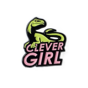 Könnte beinhalten: Ein grüner Dinosaurier mit dem Text "Clever Girl" in rosa Buchstaben auf schwarzem Hintergrund.