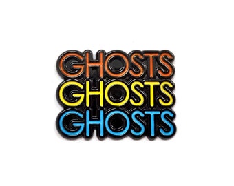 Puede incluir: Un pin de esmalte negro con la palabra "GHOSTS" repetida tres veces en naranja, amarillo y azul.