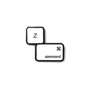 Puede incluir: Pin de esmalte blanco y negro de una tecla 'Z' de teclado de computadora y una tecla 'comando' con el símbolo de Apple.
