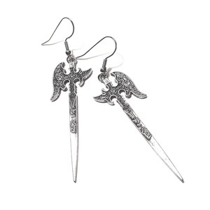 May include: A pair of silver-toned metal earrings featuring a double-bladed axe and sword design. Each earring has a long, pointed blade with intricate embossed detailing on the handle and head, suspended from a simple silver-toned wire hook.