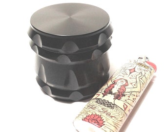 May include: A black metal grinder with a textured surface and a lighter with a mermaid design and the text "The Star".