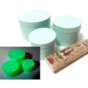 Peut inclure: Trois moulins à herbes en métal bleu clair avec un briquet représentant une sirène. Les moulins sont empilés les uns sur les autres. Le briquet est couché sur le côté. Les moulins sont en métal et ont une finition lisse. Le briquet est en plastique et a une finition texturée.