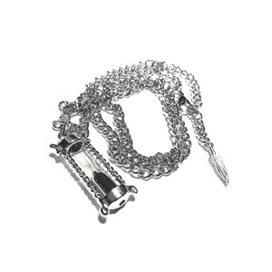 May include: A silver chain necklace with a silver hourglass pendant and a silver feather charm.