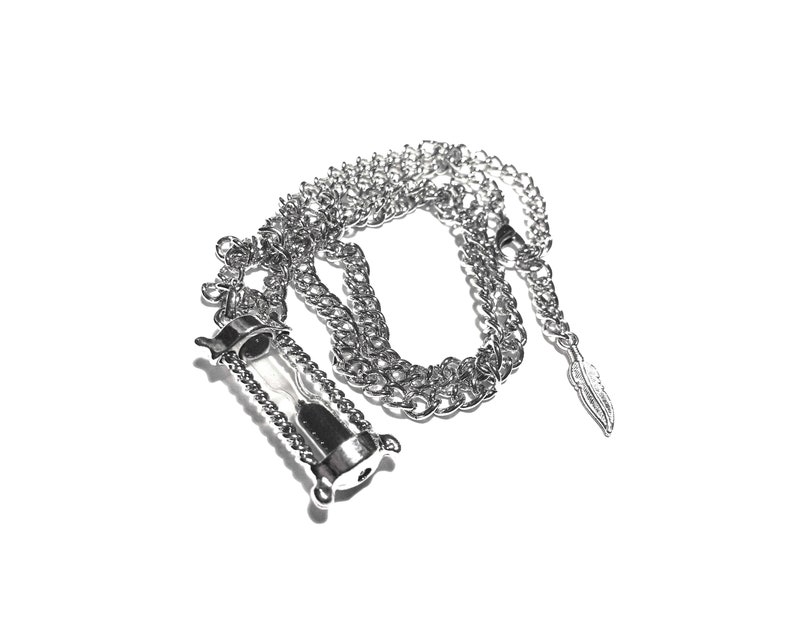 May include: A silver chain necklace with a silver hourglass pendant and a silver feather charm.