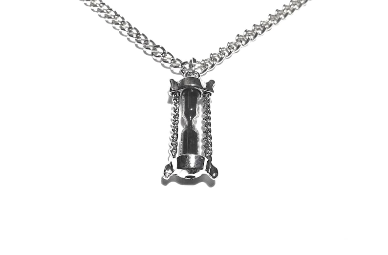 May include: A silver chain necklace with an hourglass pendant. The hourglass is suspended from the chain by two smaller chains.
