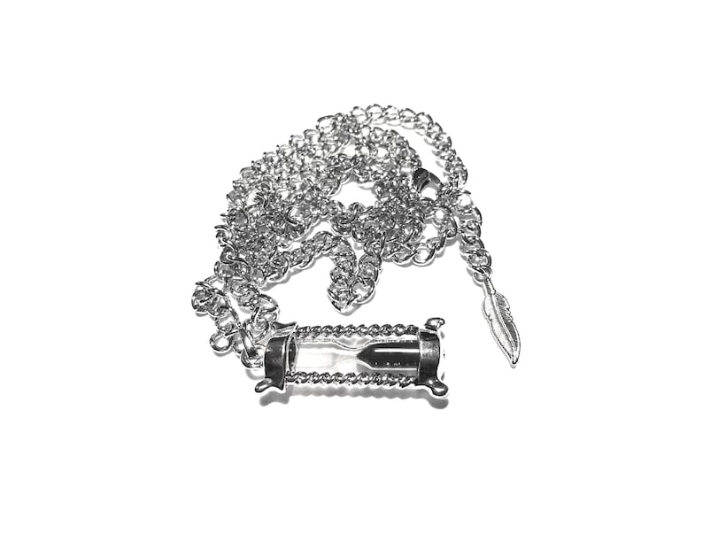 May include: A silver chain necklace with an hourglass pendant. The hourglass is filled with sand and has a silver feather charm attached to the chain.