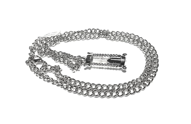 May include: A silver chain necklace with a silver hourglass pendant. The hourglass is filled with sand and has a clear glass body.