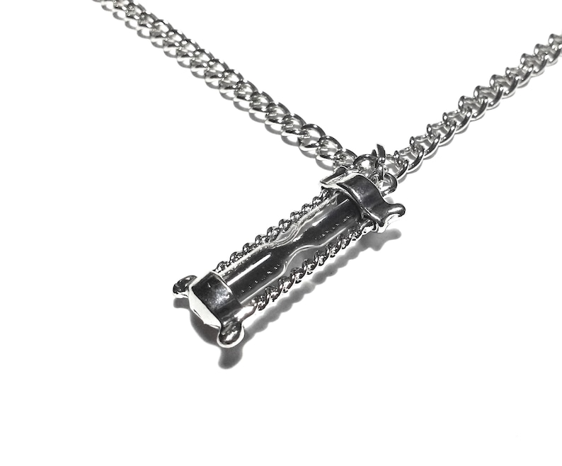 May include: A silver chain necklace with an hourglass pendant. The hourglass is made of metal and has a detailed design.