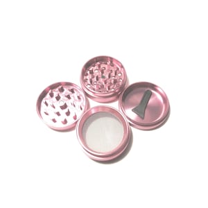 K&ouml;nnte beinhalten: Ein rosa Metall-Grinder mit vier Teilen. Der Grinder hat ein Sieb, ein Fach f&uuml;r Kr&auml;uter, ein Fach f&uuml;r Kief und einen Schaber.