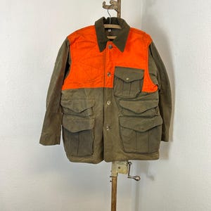 May include: A green and orange hunting jacket with multiple pockets. The jacket has a button closure and a corduroy collar.