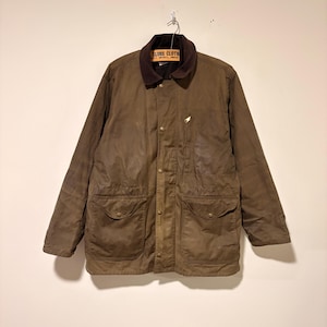 Peut inclure: Veste en coton cir&eacute; marron avec un col en velours c&ocirc;tel&eacute; et deux grandes poches avant. La veste a une fermeture boutonn&eacute;e et un petit embl&egrave;me brod&eacute; sur la poitrine. L'&eacute;tiquette indique "GLOBE CLOTH".