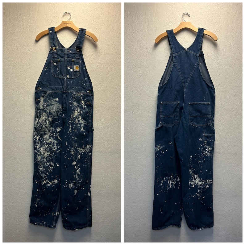 May include: A pair of blue denim overalls with white paint splatters. The overalls have adjustable straps and multiple pockets.
