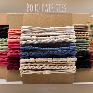May include: A set of 18 colorful hair ties in various styles, including braided, solid, and textured. The hair ties are displayed on a brown cardboard background with the text "BOHO HAIR TIES" and "BELO BOHO BABE".