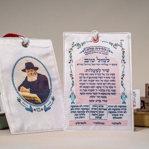 May include: A white fabric pouch with a picture of a man with a beard and a hat. The pouch has a pink and blue border with Hebrew text. The text says "For a good birth" and "A song of ascents".
