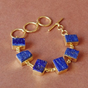 May include: A gold bracelet with a toggle clasp and six square lapis lazuli stones.