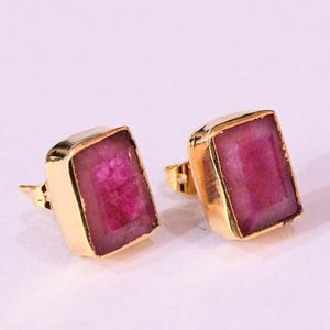 May include: A pair of gold earrings with rectangular pink gemstones.