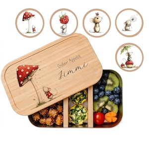 Könnte beinhalten: Eine Bambus-Lunchbox mit Edelstahl-Innenraum, mit einer skurrilen Illustration einer Maus unter einem Pilz. Der Deckel trägt den Text "Guten Appetit Jimmi". Die Lunchbox ist mit verschiedenen Lebensmitteln gefüllt, darunter Obst und kleine Quiches.