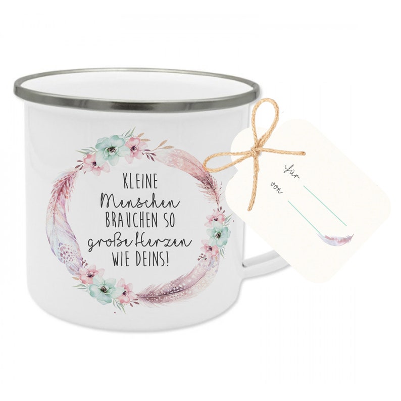 Puede incluir: Taza de esmalte blanco con un dise&ntilde;o de corona floral y el texto "Kleine Menschen brauchen so gro&szlig;e Herzen wie Deins!"  Una peque&ntilde;a etiqueta blanca est&aacute; unida al asa con el texto "F&uuml;r von"
