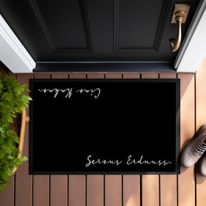 May include: Black welcome mat with white text that reads "Servus Erdnuss.  G'day, mate."