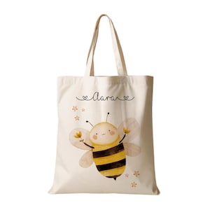May include: A white canvas tote bag with a cute cartoon bee illustration and the name "Clara" written in cursive with hearts on either side.