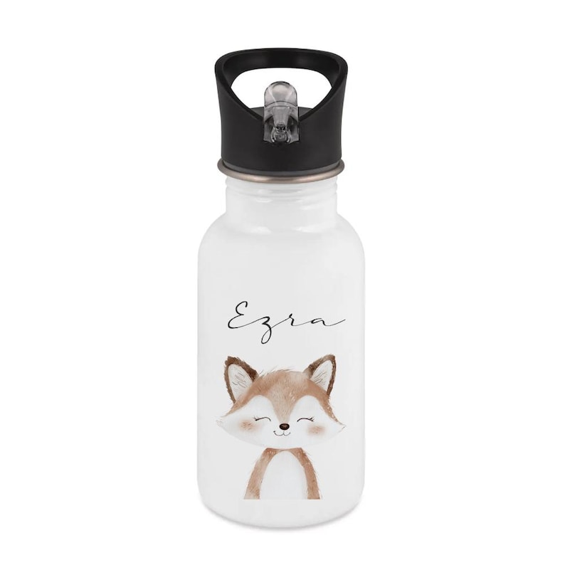 May include: White water bottle with a black lid and a cartoon fox illustration. The fox is brown and white with a smiling face. The name "Ezra" is written above the fox in a cursive font.