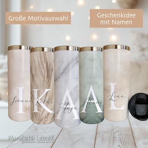 Könnte beinhalten: Fünf personalisierte isolierte Becher mit goldfarbenen Rändern und Deckeln. Jeder Becher hat ein anderes Muster, darunter Marmor und Holzmaserung, mit einem großen Initial und Namen in Weiß gedruckt. Der Text "Große Motivauswahl" und "Geschenkidee mit Namen" sind sichtbar.