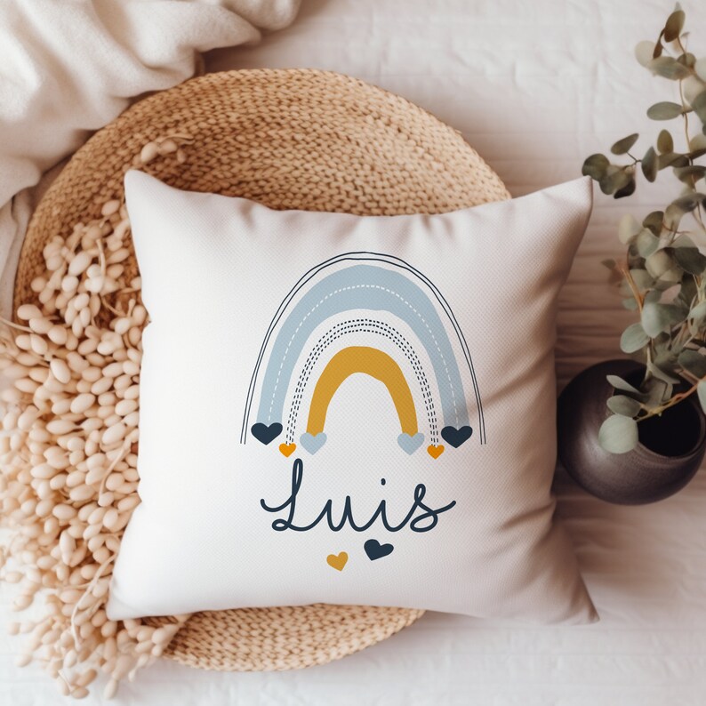 May include: White pillow with a blue and yellow rainbow design and the name "Luis" in black lettering. The rainbow has small hearts in blue and yellow.