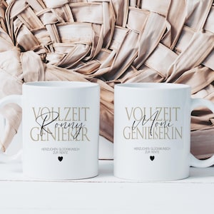 May include: Two white ceramic mugs with black and gold text. One mug says "VOLLZEIT Ronny GENIESSER" and the other says "VOLLZEIT Moni GENIESSERIN". Both mugs have the text "HERZLICHEN GLÜCKWUNSCH ZUR RENTE" and a black heart.