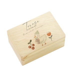 May include: A wooden box with a light wood finish. The lid has a watercolor illustration of a duck wearing a party hat and holding a gift. The text "Tereze 18. Oktober 2023 F&uuml;r deine sch&ouml;nsten Erinnerungen" is printed on the lid.