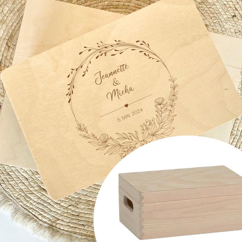 May include: A wooden box with a lid, engraved with a floral wreath design and the text "Jeannette & Micha 5 MAI 2024".