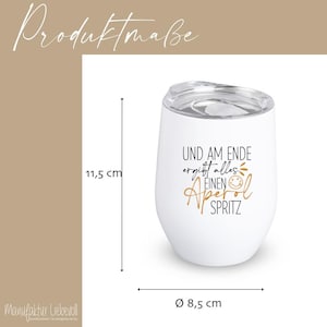 May include: White insulated wine tumbler with a clear lid. The tumbler has the text "UND AM ENDE ergibt alles EINEN Aperol SPRITZ" in gold and black. The tumbler is 4.5 inches tall and 3.3 inches in diameter.