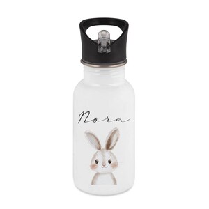 May include: White water bottle with a black lid. The bottle features the name "Nora" in cursive script and a watercolor illustration of a bunny. The bunny has brown ears and a sweet expression.