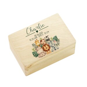 Op de afbeelding: Een houten bewaardoos met een lichte houtkleur. De doos heeft een groen en bruin jungledierontwerp met de naam "Charlie" en de datum "08.06.2023 10:23 Uhr 3210 G 52 CM" gedrukt op de deksel.