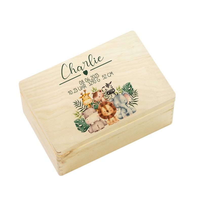 Op de afbeelding: Een houten bewaardoos met een lichte houtkleur. De doos heeft een groen en bruin jungledierontwerp met de naam "Charlie" en de datum "08.06.2023 10:23 Uhr 3210 G 52 CM" gedrukt op de deksel.