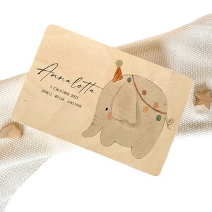 May include: A wooden birth announcement plaque with a hand-painted illustration of a grey elephant wearing a party hat. The plaque reads "Annalotta 7. Oktober 2023 2998 G 49 CM 2:40 UHR".