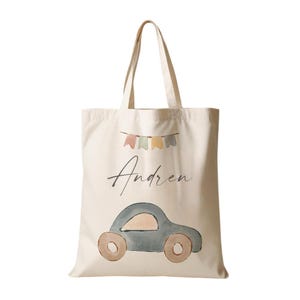 Peut inclure: Un sac fourre-tout en toile beige avec une voiture bleue et des drapeaux color&eacute;s imprim&eacute;s dessus. Le sac porte le nom "Andren" imprim&eacute; dessus.