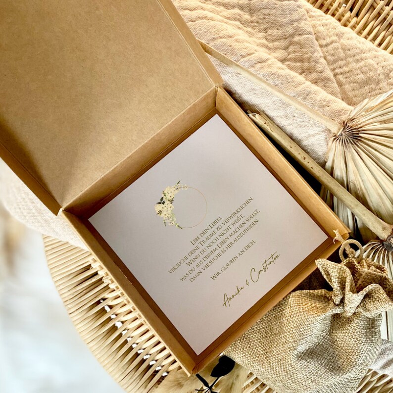 May include: A white card with a gold circle and floral design. The card has a message that reads "Live your life. Try to make your dreams come true. If you are not sure what you want to do with your life, try to find out. We believe in you." The card is signed "Annika & Constantin".