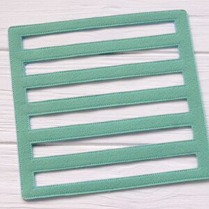 May include: A light green felt board with six rectangular cutouts. The board is perfect for organizing small items or creating a visual display.