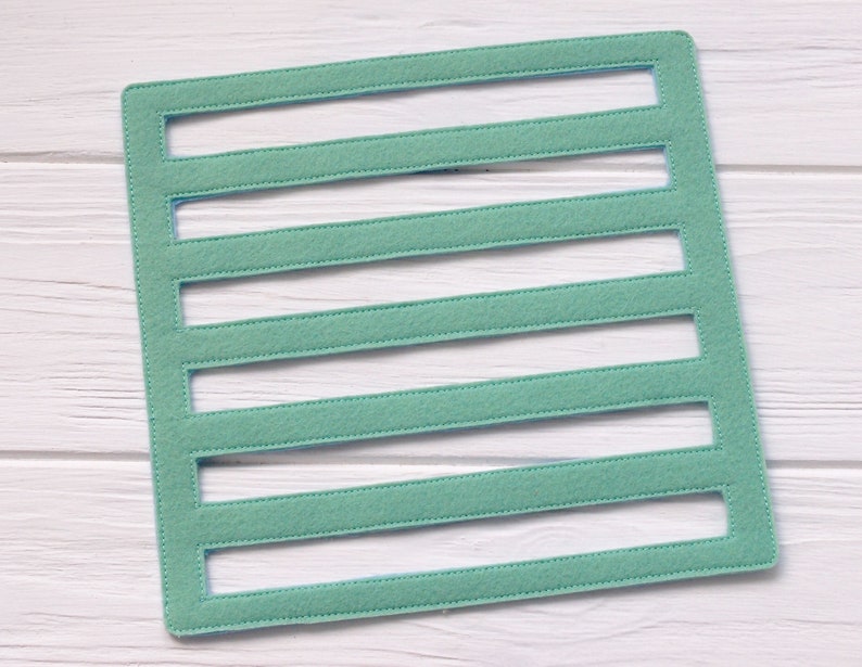 May include: A light green felt board with six rectangular cutouts. The board is perfect for organizing small items or creating a visual display.