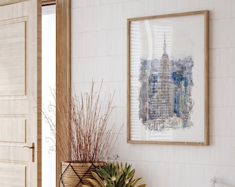 Puede incluir: Una pintura de acuarela enmarcada de una ciudad con edificios altos, incluyendo un rascacielos, en tonos azules y grises. La pintura está colocada contra una pared blanca con una puerta de madera y una planta en maceta en primer plano.