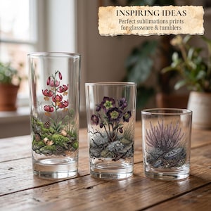 May include: Three clear glass tumblers of varying heights, each featuring a detailed botanical illustration. The designs include red lily-like flowers, dark purple hellebore flowers, and a cluster of purple heather, all set against mossy rocks.