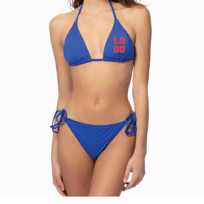 May include: A royal blue bikini set featuring a triangle top with the word "LOGO" printed in bold red letters on the left cup. The bikini bottom includes adjustable side ties on both hips, providing a secure fit for this two-piece swimwear.