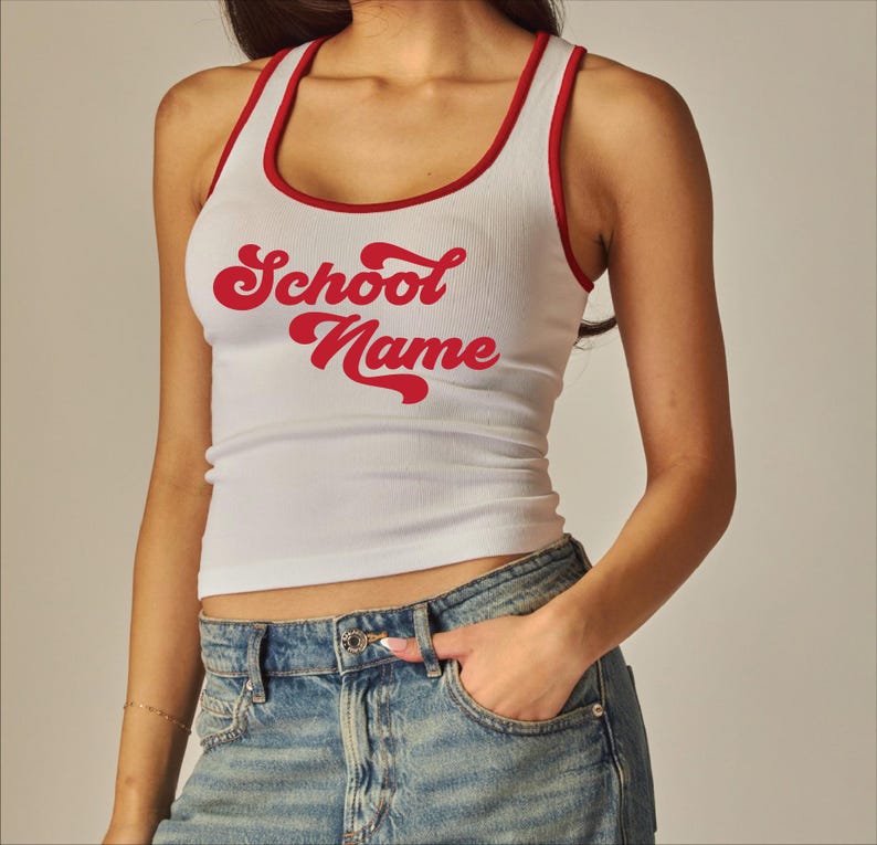 May include: White ribbed tank top with red trim and the words "School Name" in red script. The tank top is a fitted style.