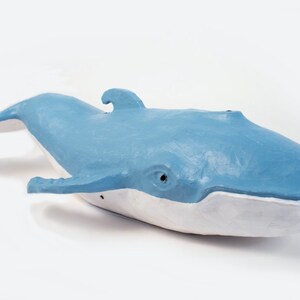 May include: A blue and white whale sculpture made of paper mache. The whale is swimming with its mouth open.