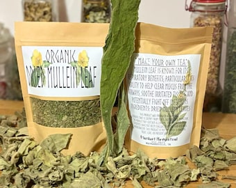 May include: Two tan pouches filled with organic dried mullein leaf, featuring labels with text including Organic Dried Mullein Leaf and Make Your Own Tea. A single large, dried green leaf stands upright between the pouches, surrounded by loose dried leaves.