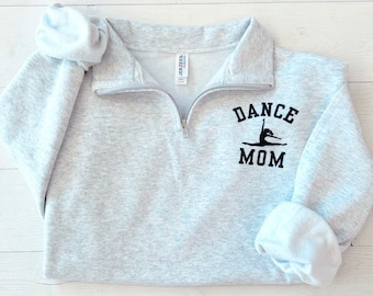 以下が含まれることがあります： 黒のダンサーのグラフィックと「DANCE MOM」のテキストが書かれたグレーのトレーナーです。