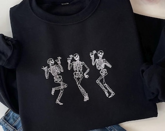 May include: Black sweatshirt with a white graphic of three skeletons dancing and holding drinks. The skeletons are outlined in white and have a simple design.
